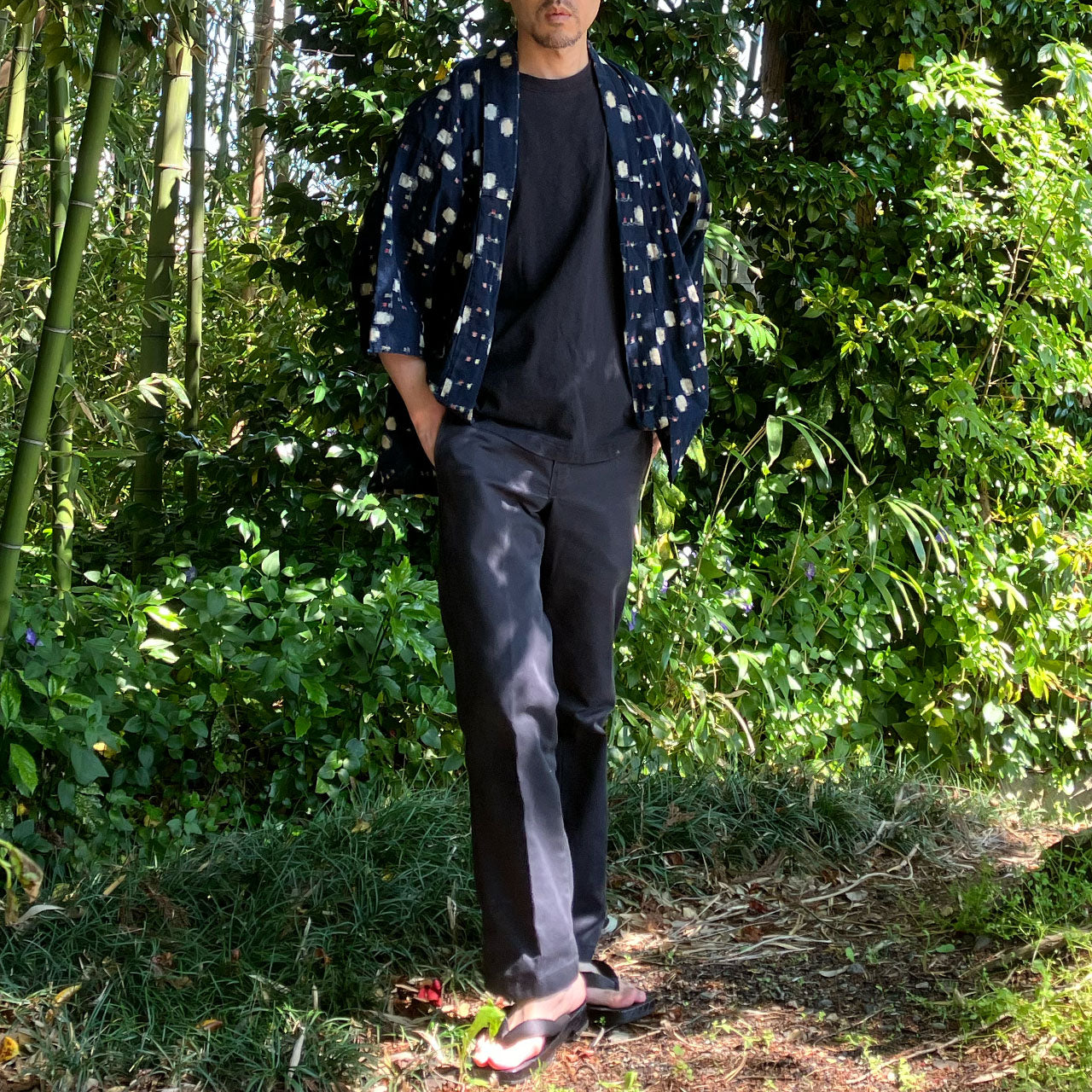 Full view of a man wearing a noragi, blending harmoniously with bamboo groves and nature