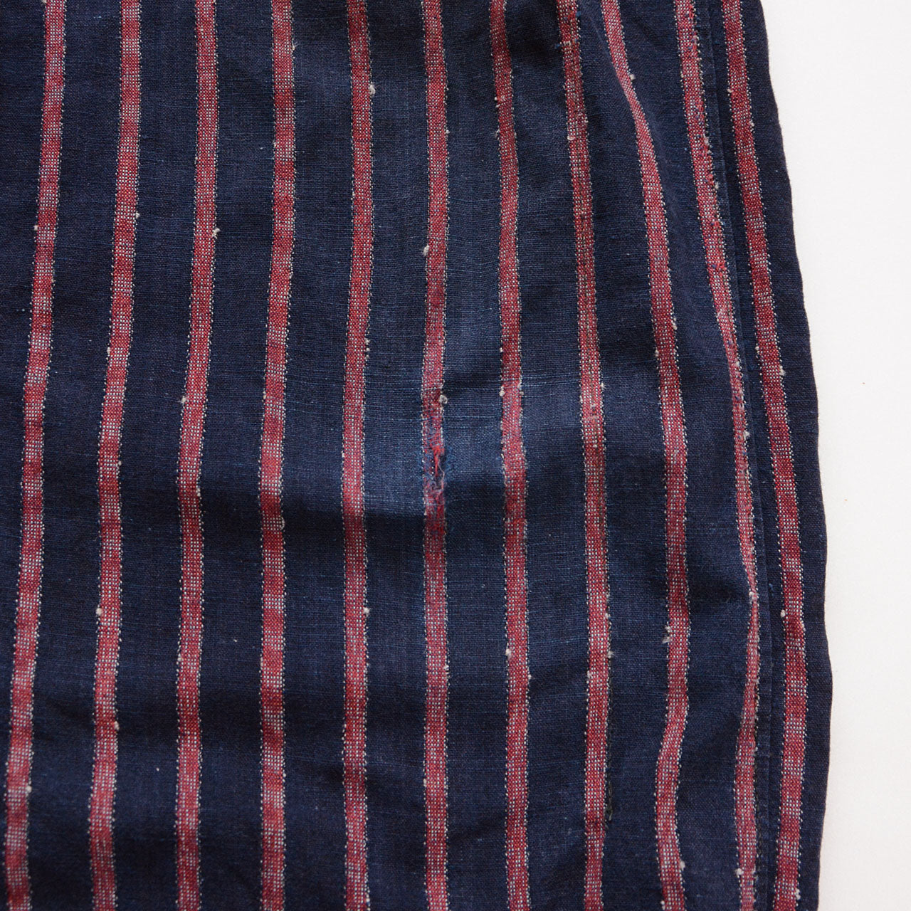 Faded indigo Japanese monpe trousers with repair patches and metal hooks at the hems