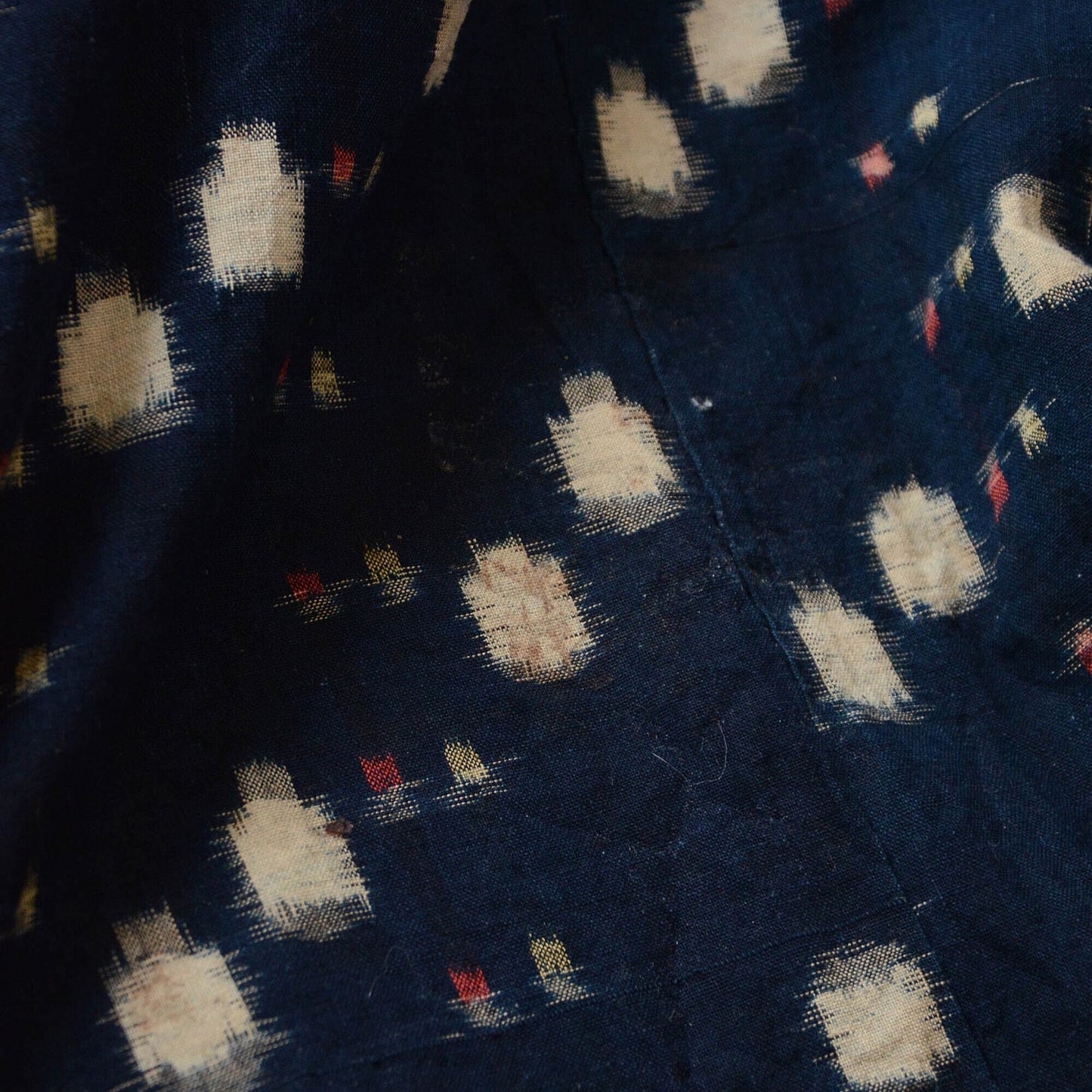 Close-up of aged indigo kasuri fabric, where the wear and stains enhance its unique character