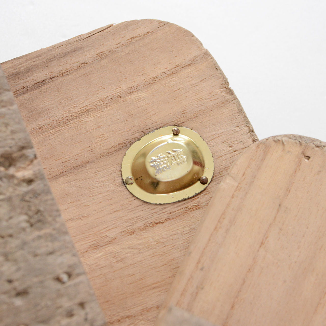 Brass Tokusen hardware medallion on the top surface of Aizu Paulownia geta, a mark of premium craftsmanship