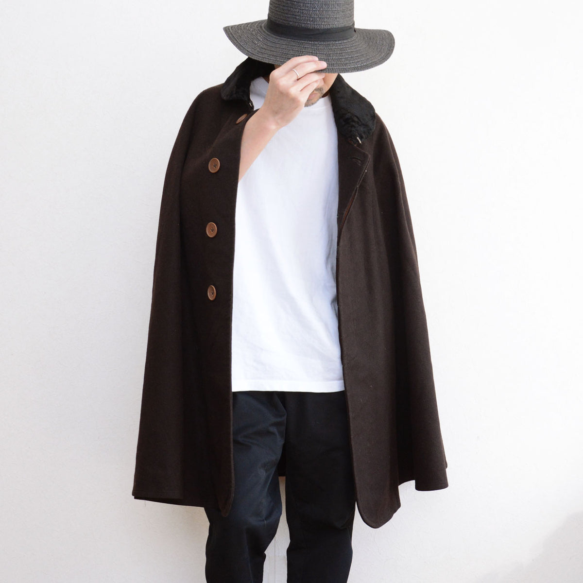Dark brown vintage mantle with brown buttons, a white top and dark trousers