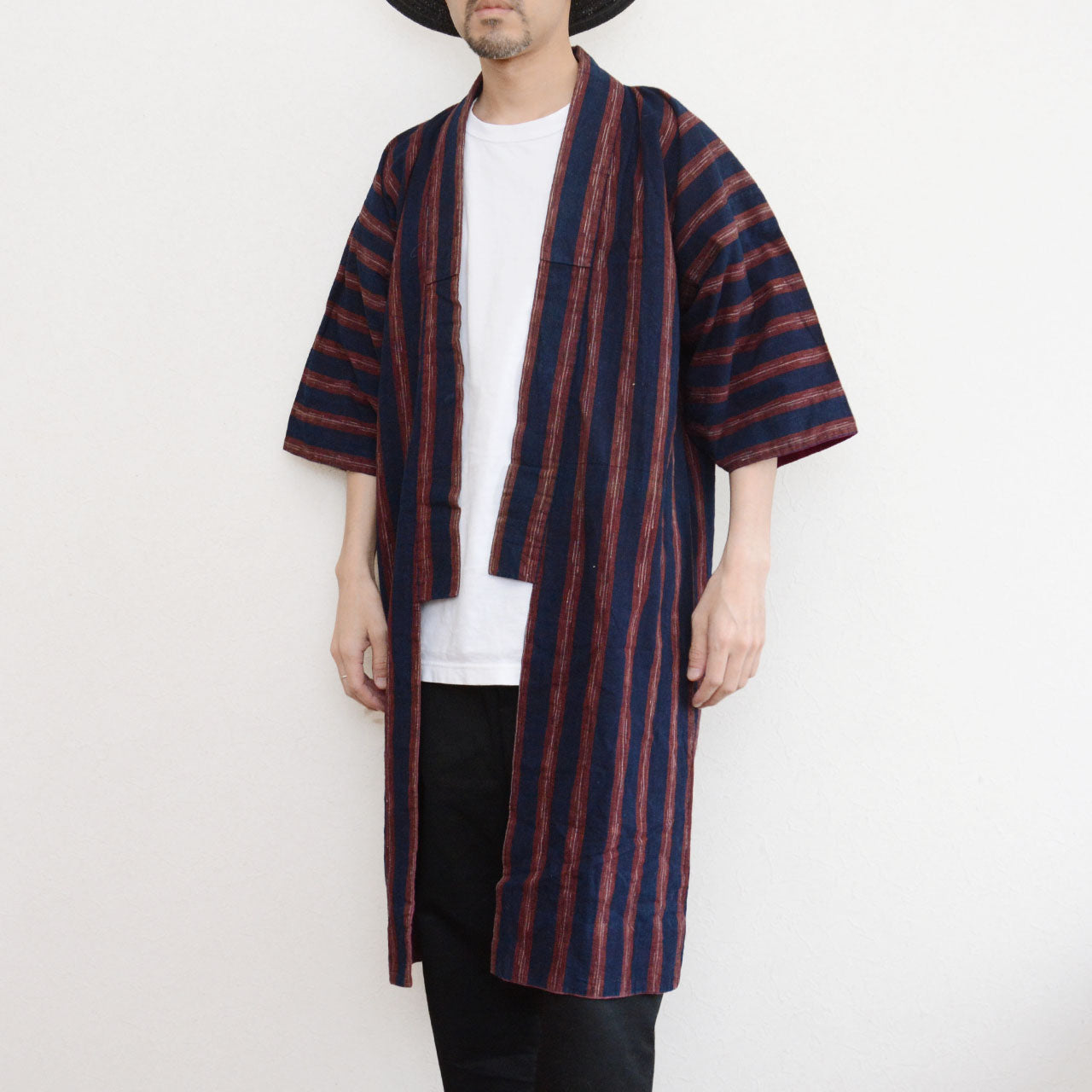 Vintage Japanese noragi jacket worn by a male model, front view alternate — indigo-dyed cotton with bold red stripe, open-front wrap construction, Tohoku, early Showa era