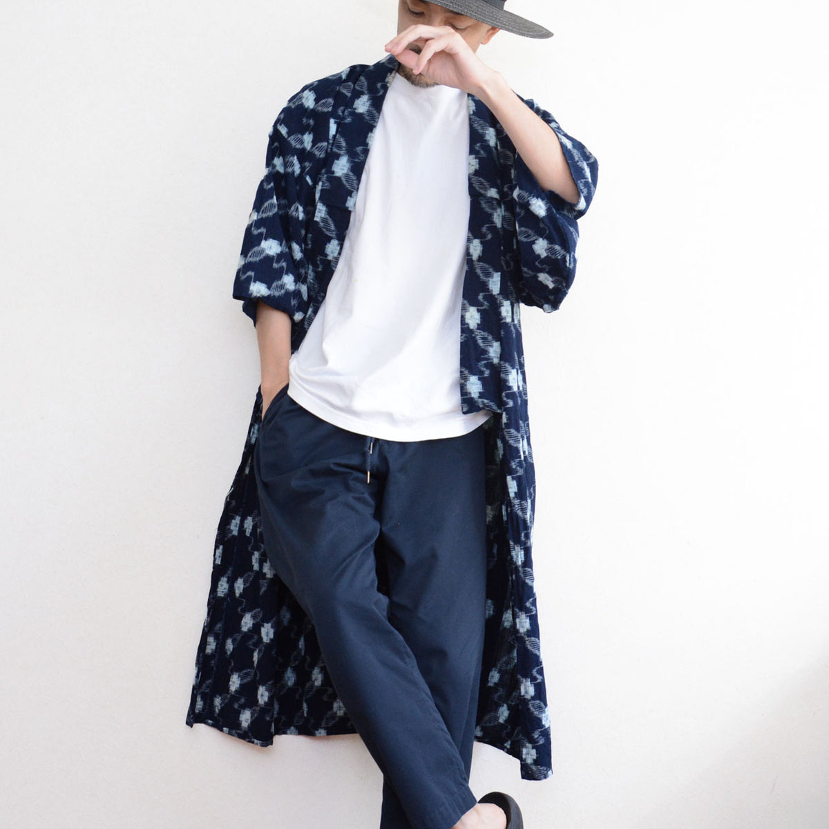 Male model styling an indigo kasuri cotton kimono robe with a grey cap, white T-shirt, navy trousers, and sandals