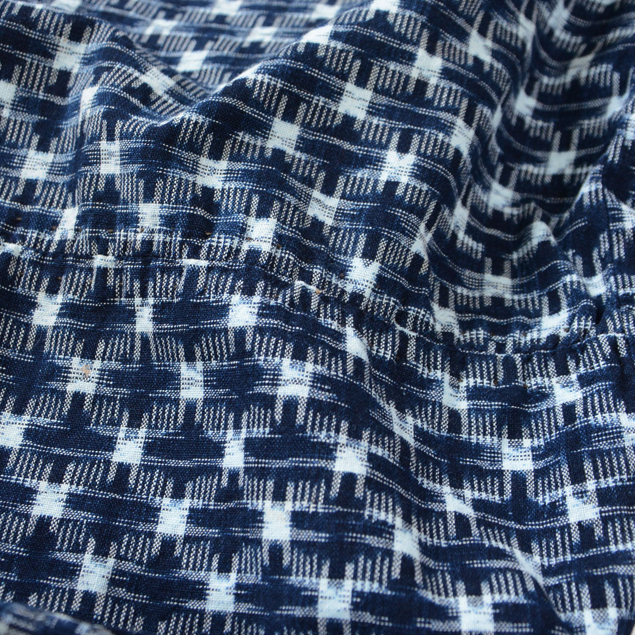 Indigo kasuri cotton fabric close-up, navy and white ikat check weave, vintage Japanese textile