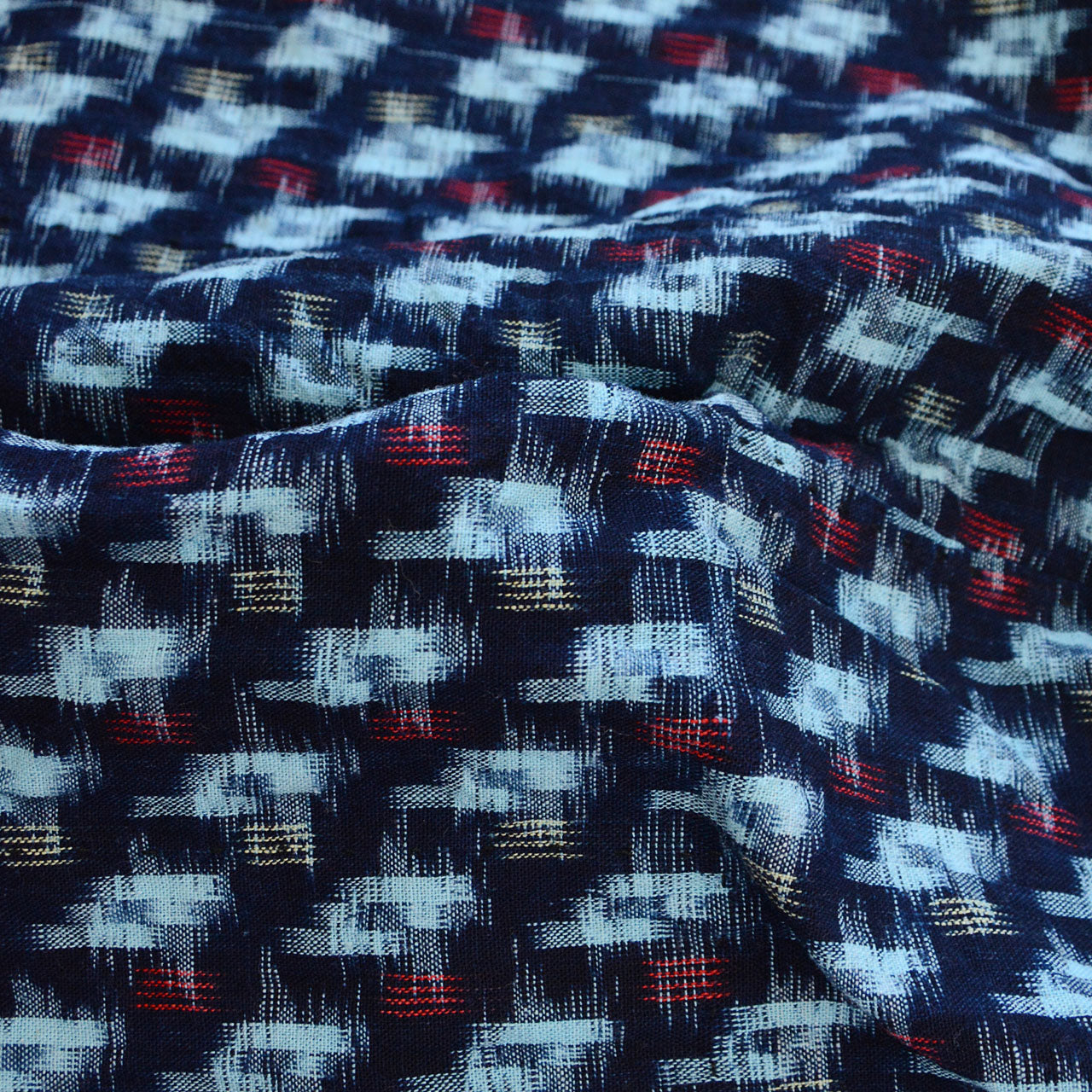 Indigo kasuri cotton fabric close-up, navy and white ikat weave, hand-dyed thread texture, Mid-Showa era Japanese vintage textile