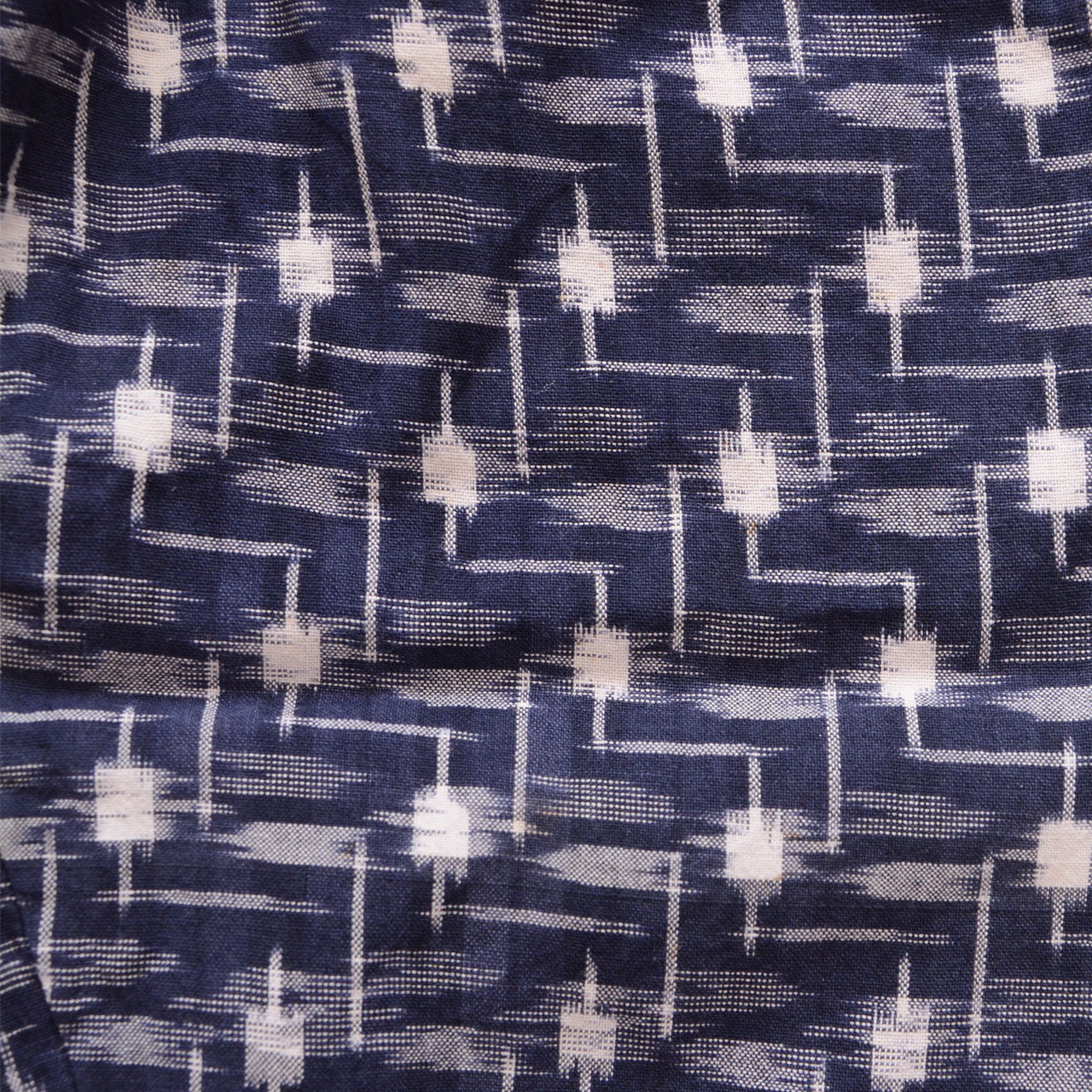 Close-up of kasuri ikat weave, navy and white cotton, geometric pattern with characteristic blur and irregularity of Japanese hand-woven textile