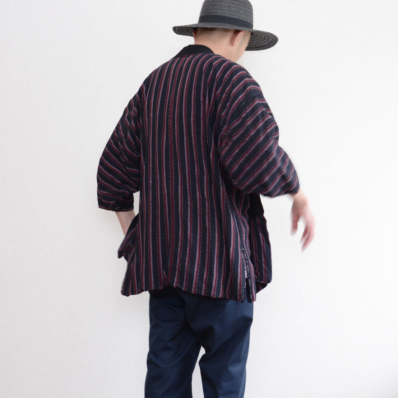Back view of a Japanese vintage striped noragi worn with a black hat and dark trousers