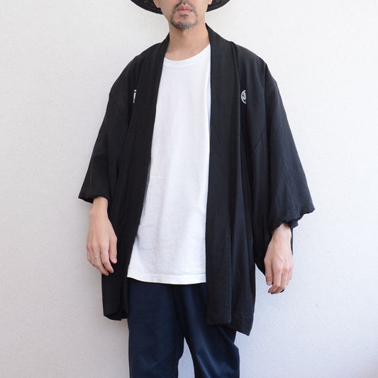 Model wearing men's black silk itsutsumon haori jacket, front view