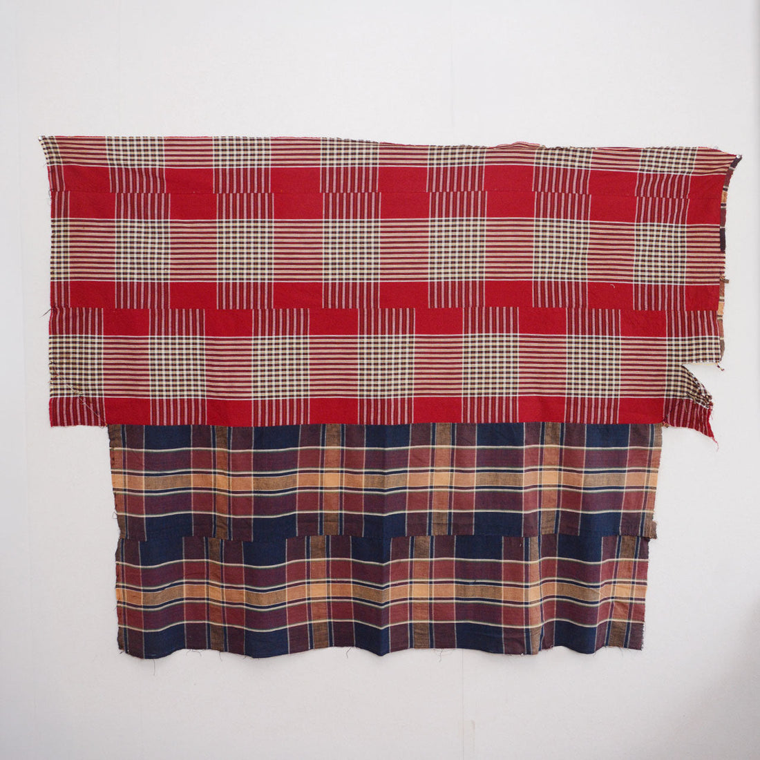Full front view of vintage Japanese futon cover displayed on wall — crazy pattern with red plaid upper half and navy plaid lower half, mid-Showa era cotton textile