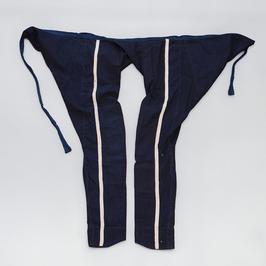 Indigo cotton momohiki laid flat, showing natural-colored stripe detail on both legs