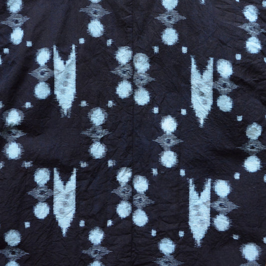 Close-up of indigo kasuri cotton fabric showing abstract dot and geometric ikat pattern, vintage Japanese noragi jacket
