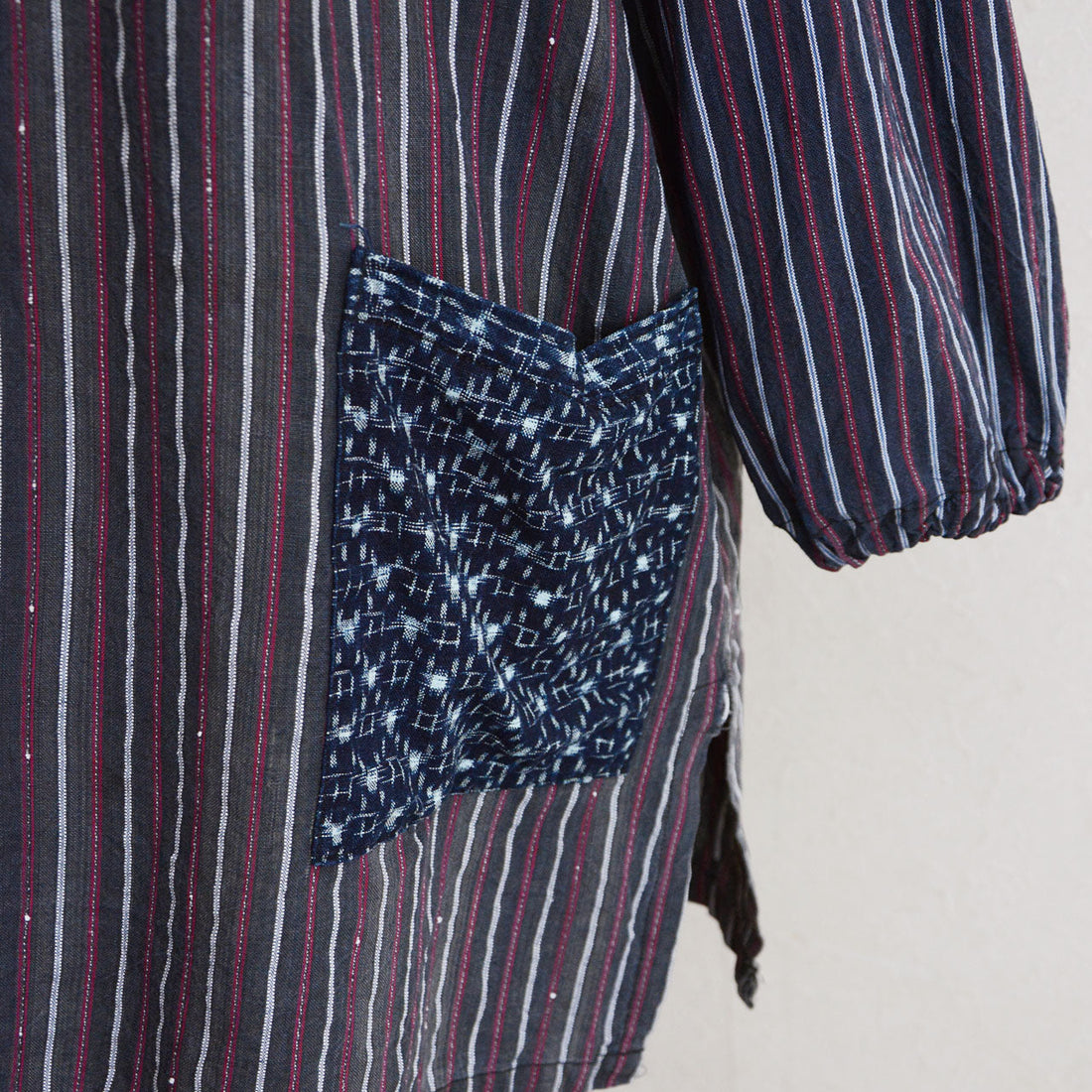 Indigo kasuri pocket close-up on Showa-era stripe cotton tunic, hand-stitched vintage Japanese fabric
