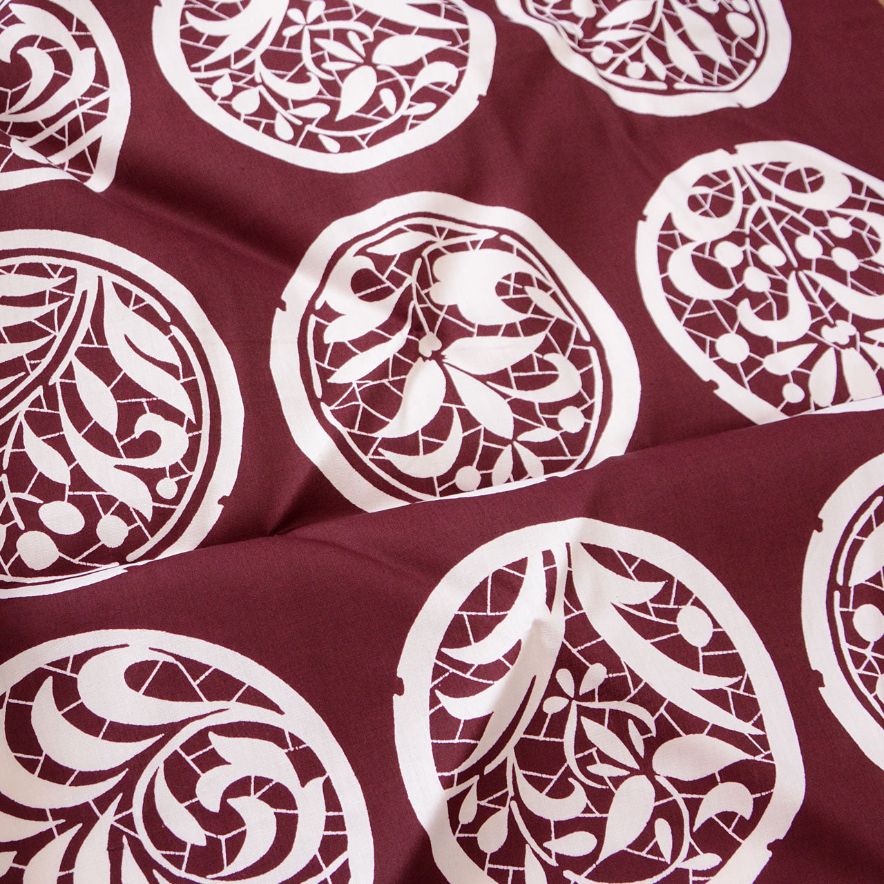 Vintage Japanese furoshiki with botanical crest motifs on burgundy cotton fabric