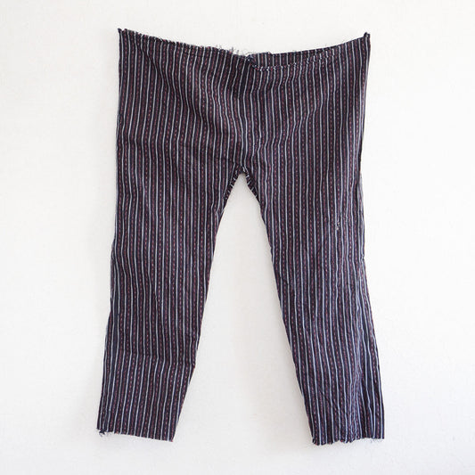 Front view of vintage Japanese monpe pants with striped cotton fabric, displayed on the wall. Showcasing the cropped waist and hem design typical of mid-Showa era workwear.