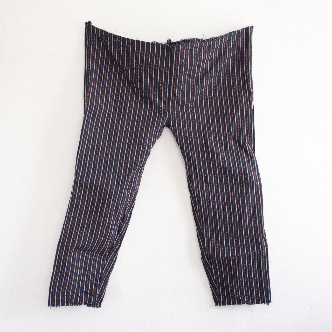 Back view of vintage Japanese monpe pants, showcasing the striped cotton fabric and the unique cut waist and hem design. Displayed on the wall, highlighting the authentic, workwear-inspired design of the mid-Showa era.