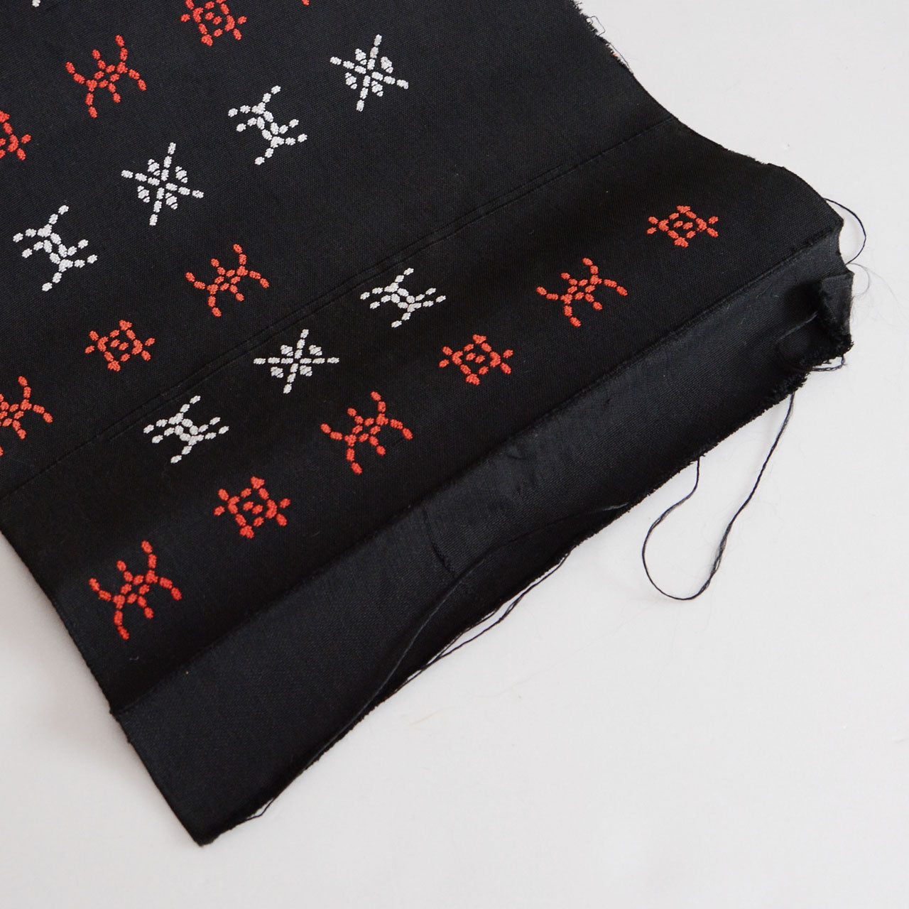 Vintage Japanese cotton textile featuring red and white embroidery on a black background