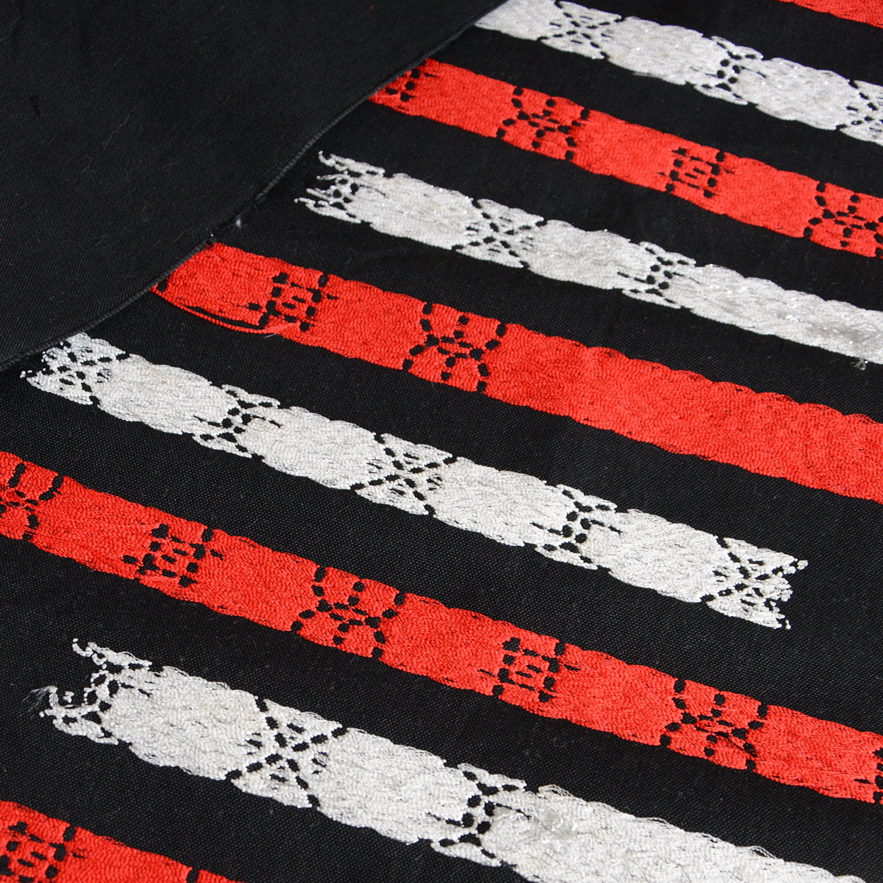 Long narrow cotton fabric roll with embroidered decoration, stored in uncut length