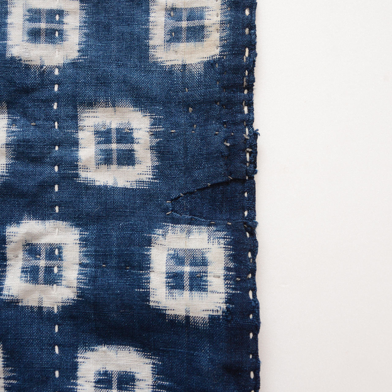 Indigo kasuri cotton fabric with visible sashiko embroidery and repairs