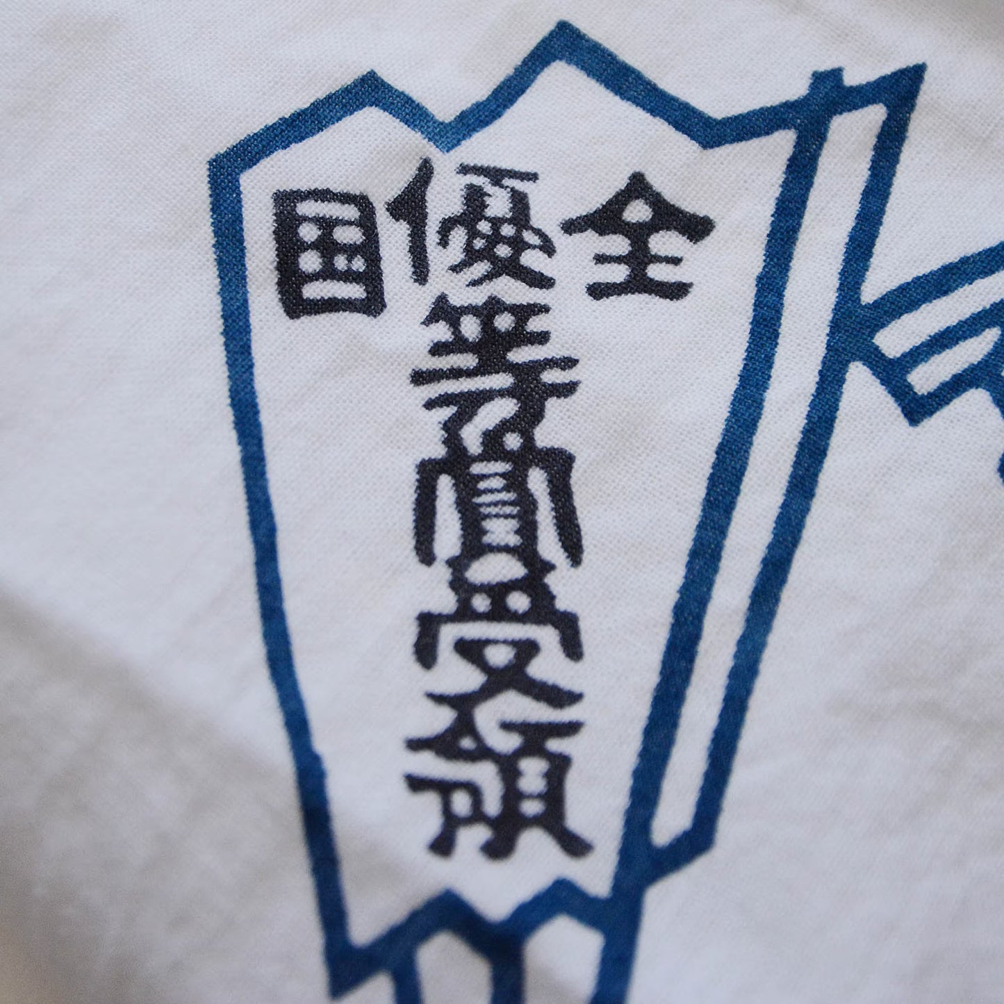 Zoomed image of a hand towel with a beautiful, powerful kanji character on a folding fan
