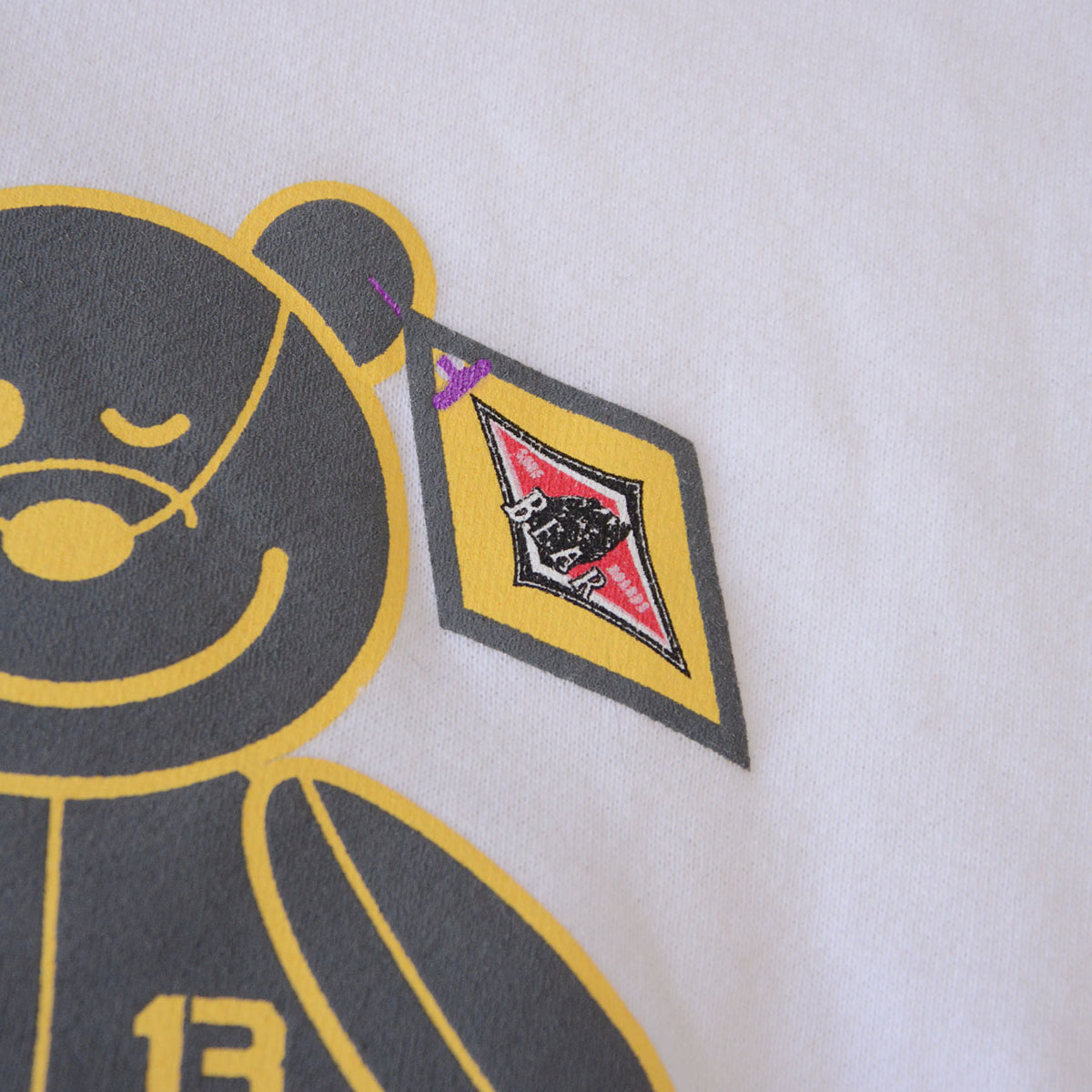 Diamond BEAR logo graphic beside bear print on white sweatshirt