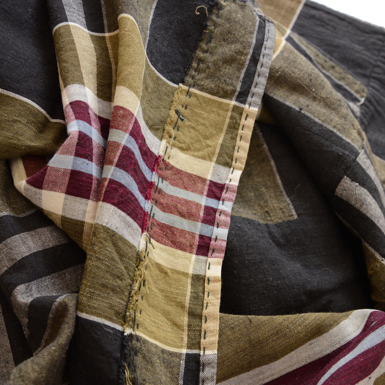 Vintage Japanese boro futon-gawa fabric, plaid cotton in black, khaki, burgundy and white, draped and folded showing red hand-stitched repair and khaki patch detail, Showa era
