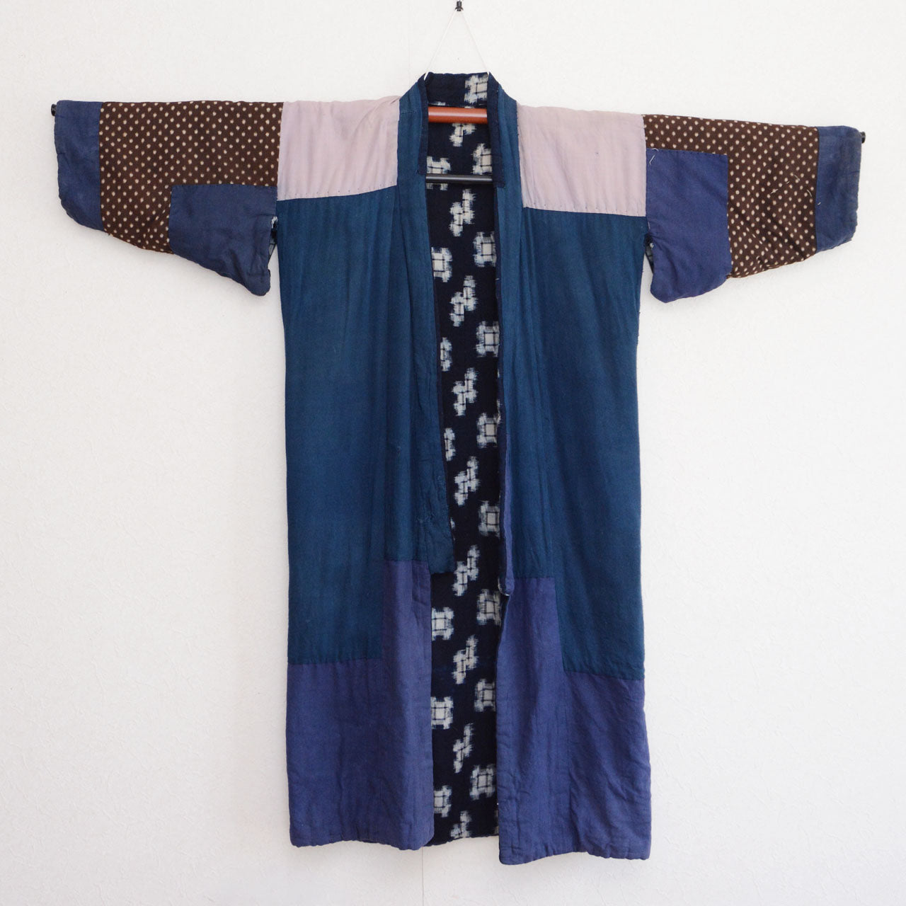 Back side of vintage Japanese hanten padded jacket on hanger, front view, indigo kasuri fabric