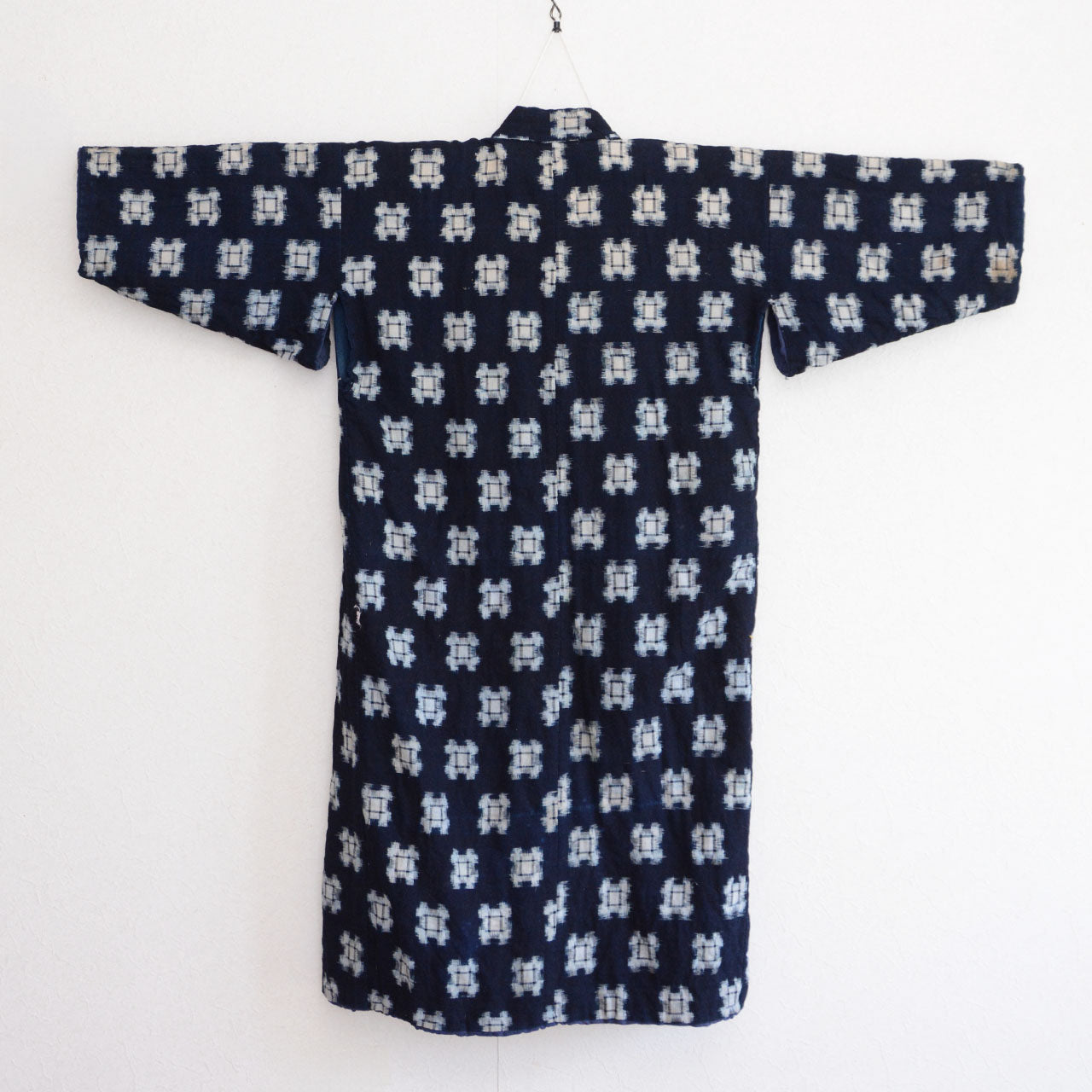 Front side of vintage Japanese hanten padded jacket on hanger, rear view, indigo kasuri fabric