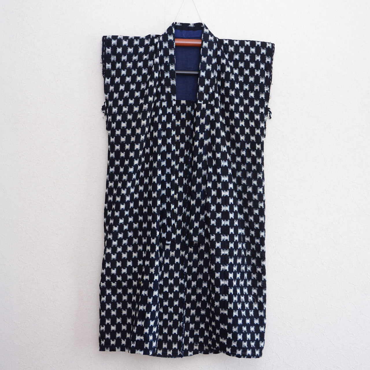 Indigo kasuri cotton haori vest on hanger, navy and white ikat weave pattern, front view