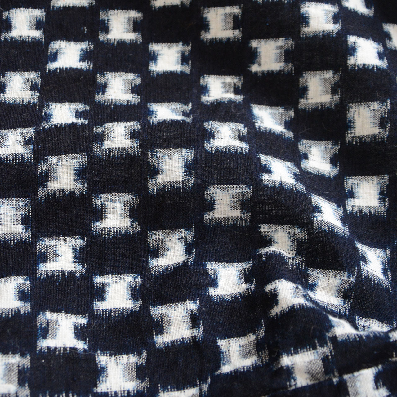 Close-up of indigo kasuri cotton fabric, hand-woven ikat pattern with natural dye variation