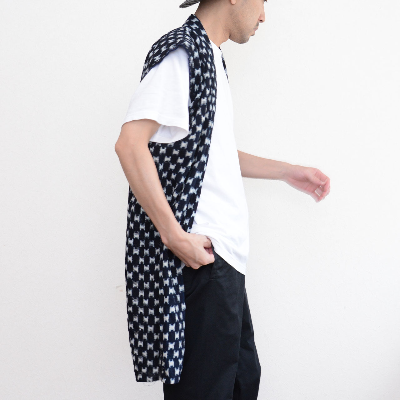 Indigo kasuri sleeveless haori vest styled with white t-shirt, black trousers and brimmed hat, side view