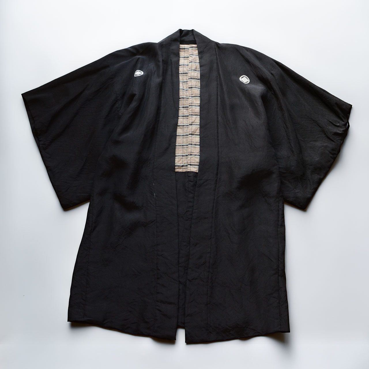 Men's black itsutsumon haori jacket laid flat, front view, with checkered lining visible at center opening, Japan vintage