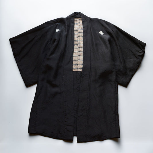 Men's black itsutsumon haori jacket laid flat, front view, with checkered lining visible at center opening, Japan vintage