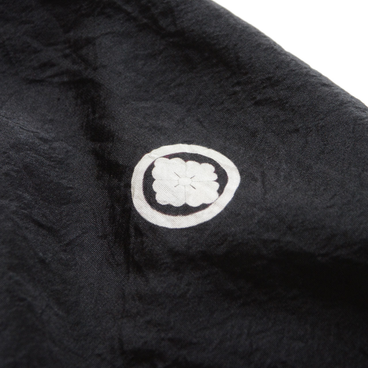 Close-up of white dyed family crest on black haori — maru ni mokkou (wood sorrel floral crest within circle) kamon, Showa era Japan vintage