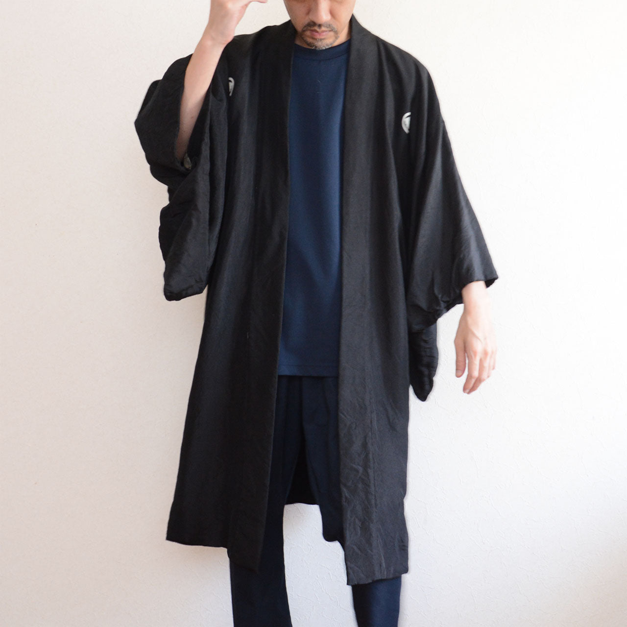 Model wearing men's black itsutsumon haori jacket, front view, long silhouette at 103.5 cm, styled over navy tee and dark trousers, model height 171 cm