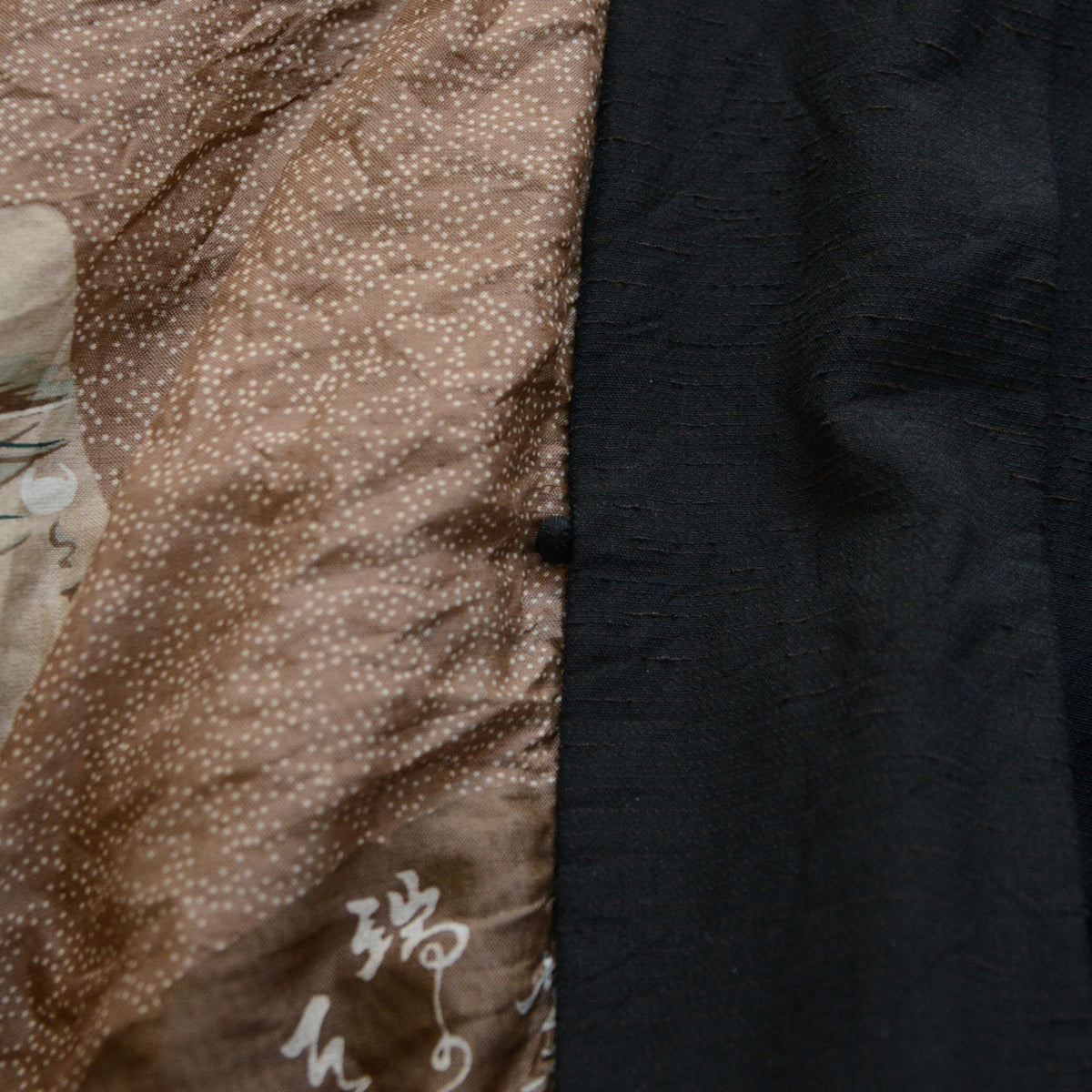Black vintage men's haori jacket with a haori cord loop and brown lining featuring white dots and Japanese calligraphy