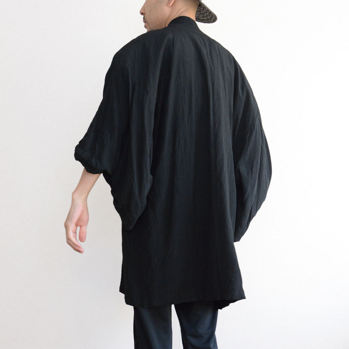 Men's black Japanese vintage haori jacket with flowing drape, voluminous sleeves, and a center seam, paired with black trousers