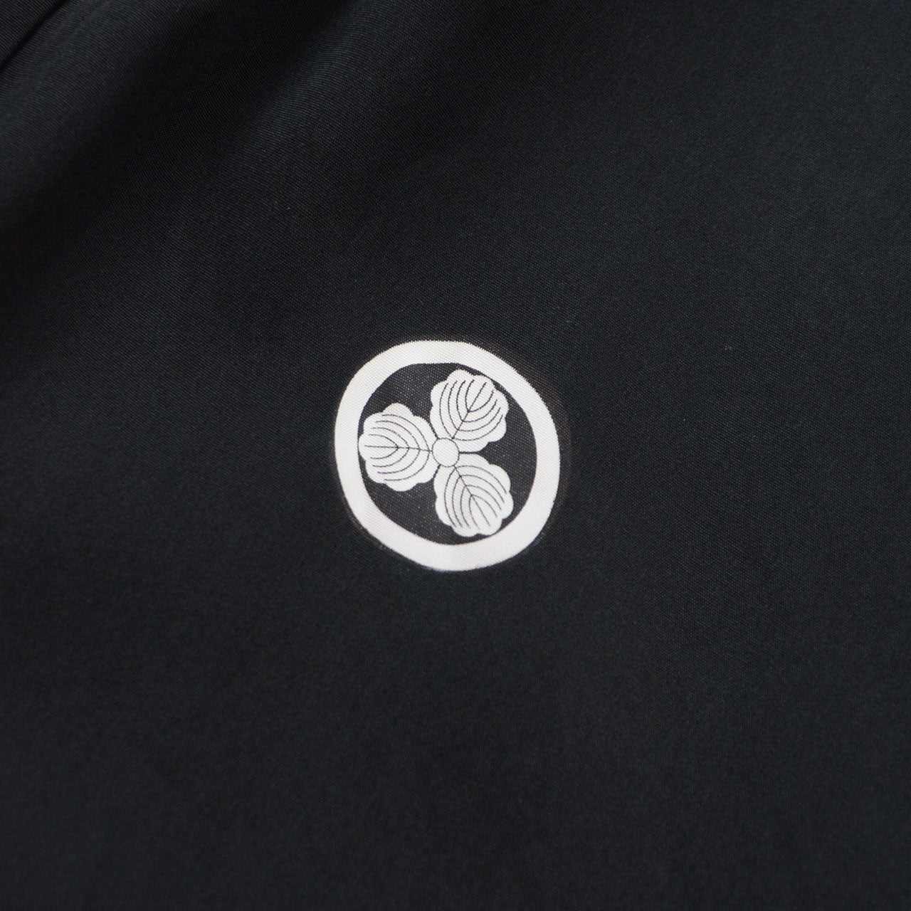 Maru ni Mitsu Kashiwa kamon, white Japanese family crest featuring three oak leaves enclosed in a circle, dyed on black silk haori fabric, Japan vintage