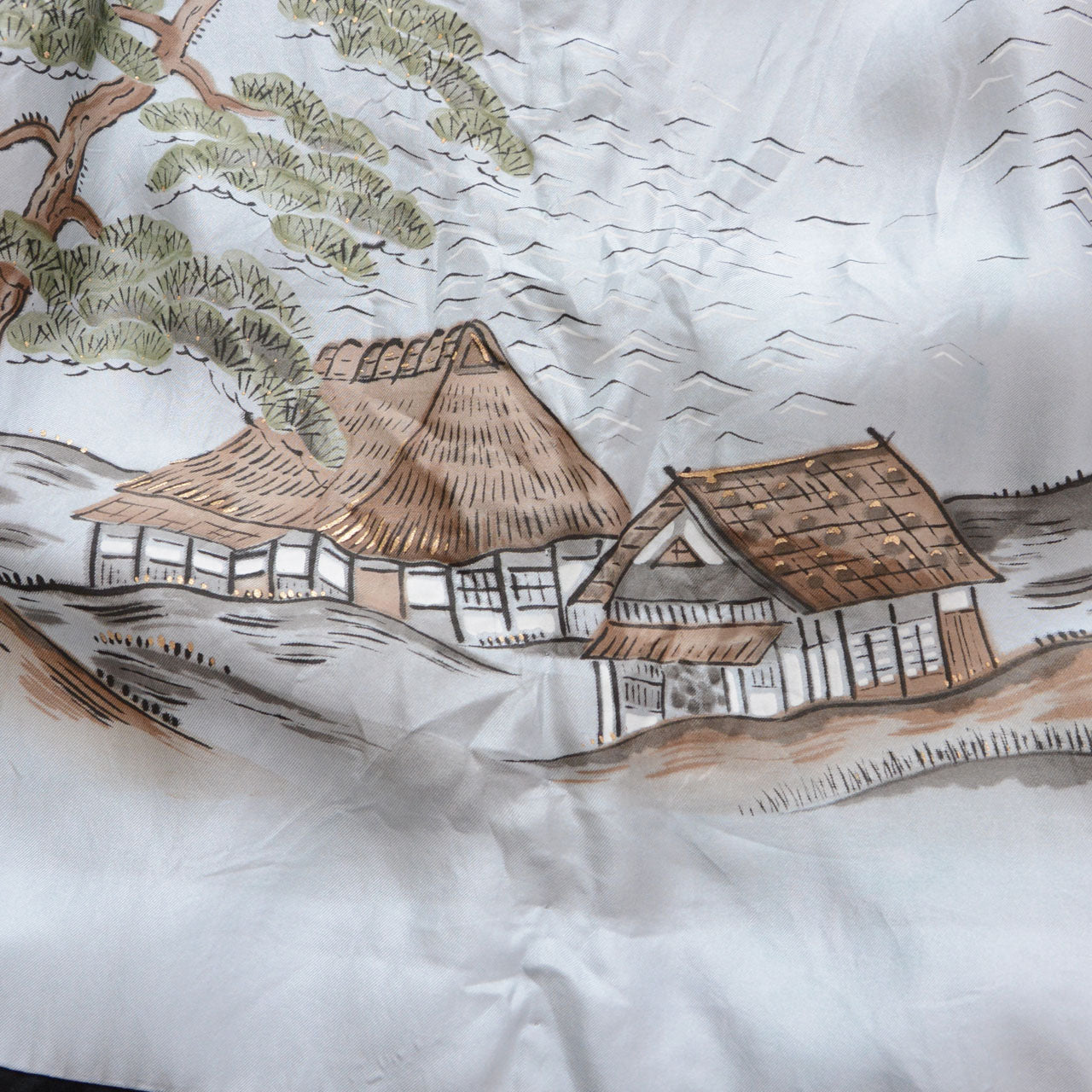 Pale blue silk haori lining (haura), close detail of hand-painted thatched farmhouse and secondary structure with pine tree, brown earth tones on light blue ground, Japanese sansui landscape textile art