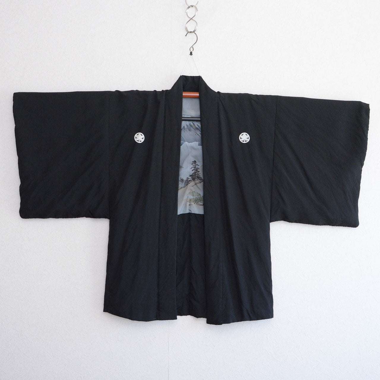 Men's black silk itsutsumon haori on kimono hanger, front view