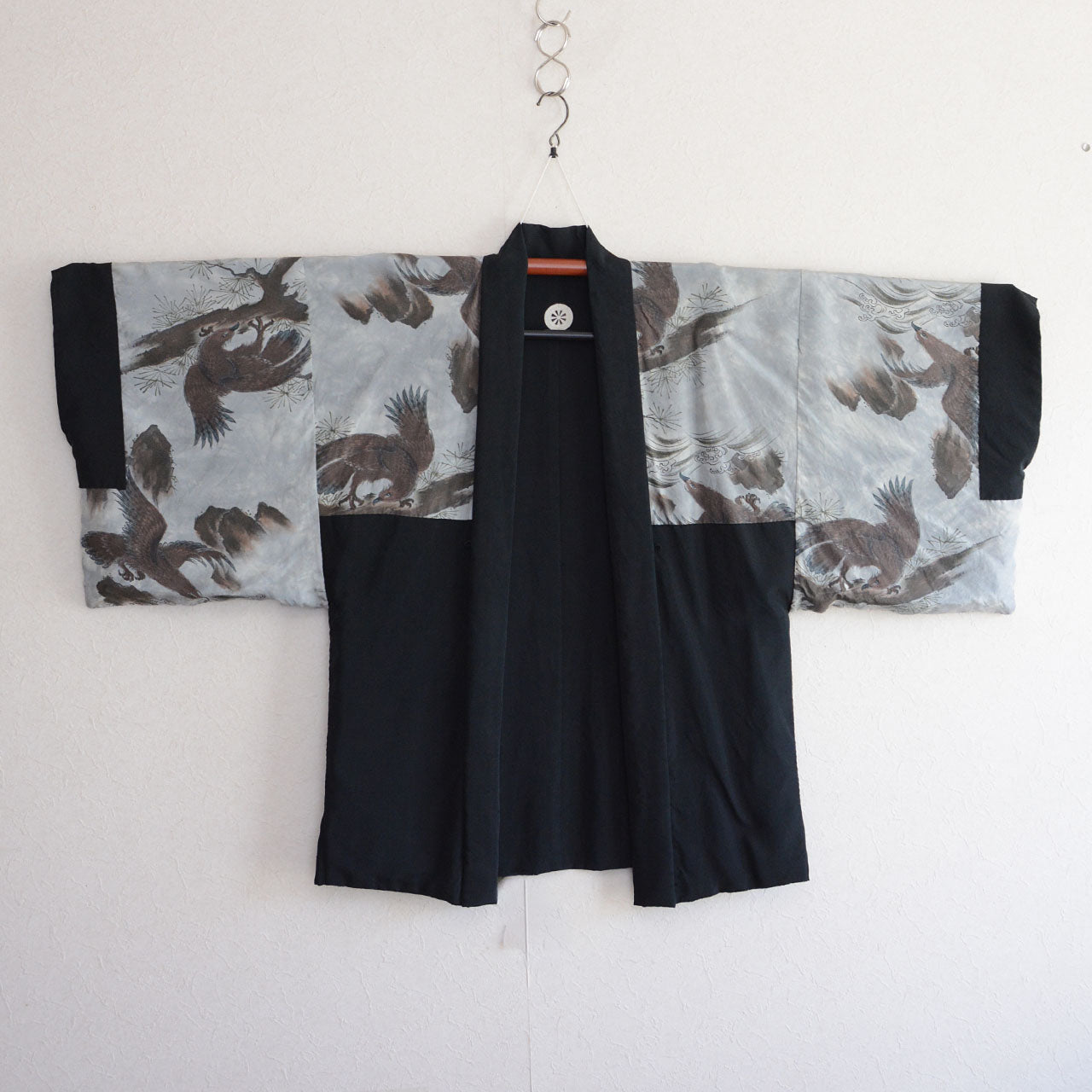 Inside-out view of black montsuki haori lining, multiple eagles soaring over waves and rocks, Japanese ink painting style, silver-grey silk