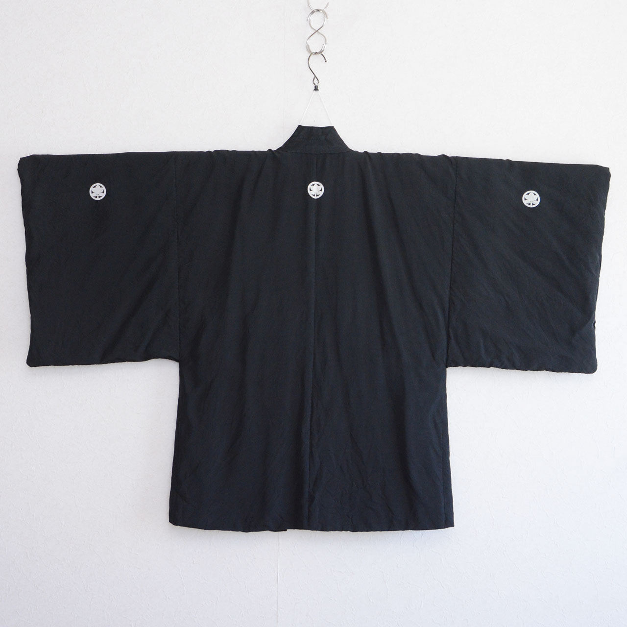Men's black silk itsutsumon haori on kimono hanger, back view