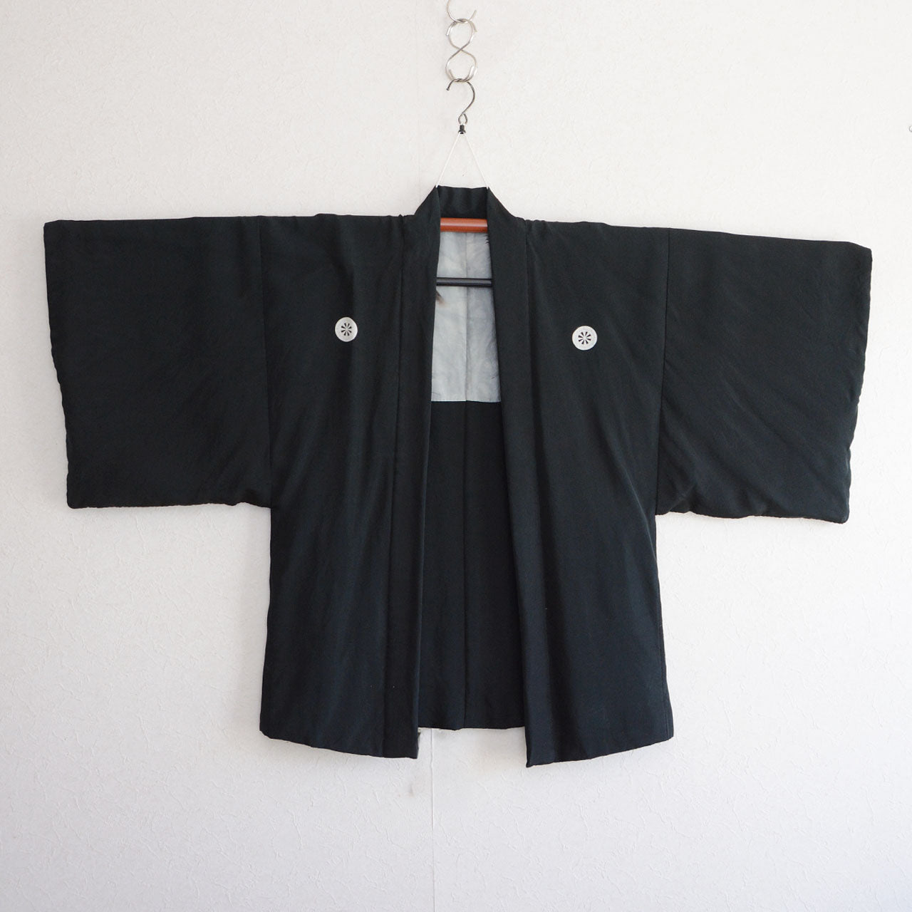 Front view of black silk haori laid flat, five white kamon crests on chest and shoulders, montsuki, Japan vintage