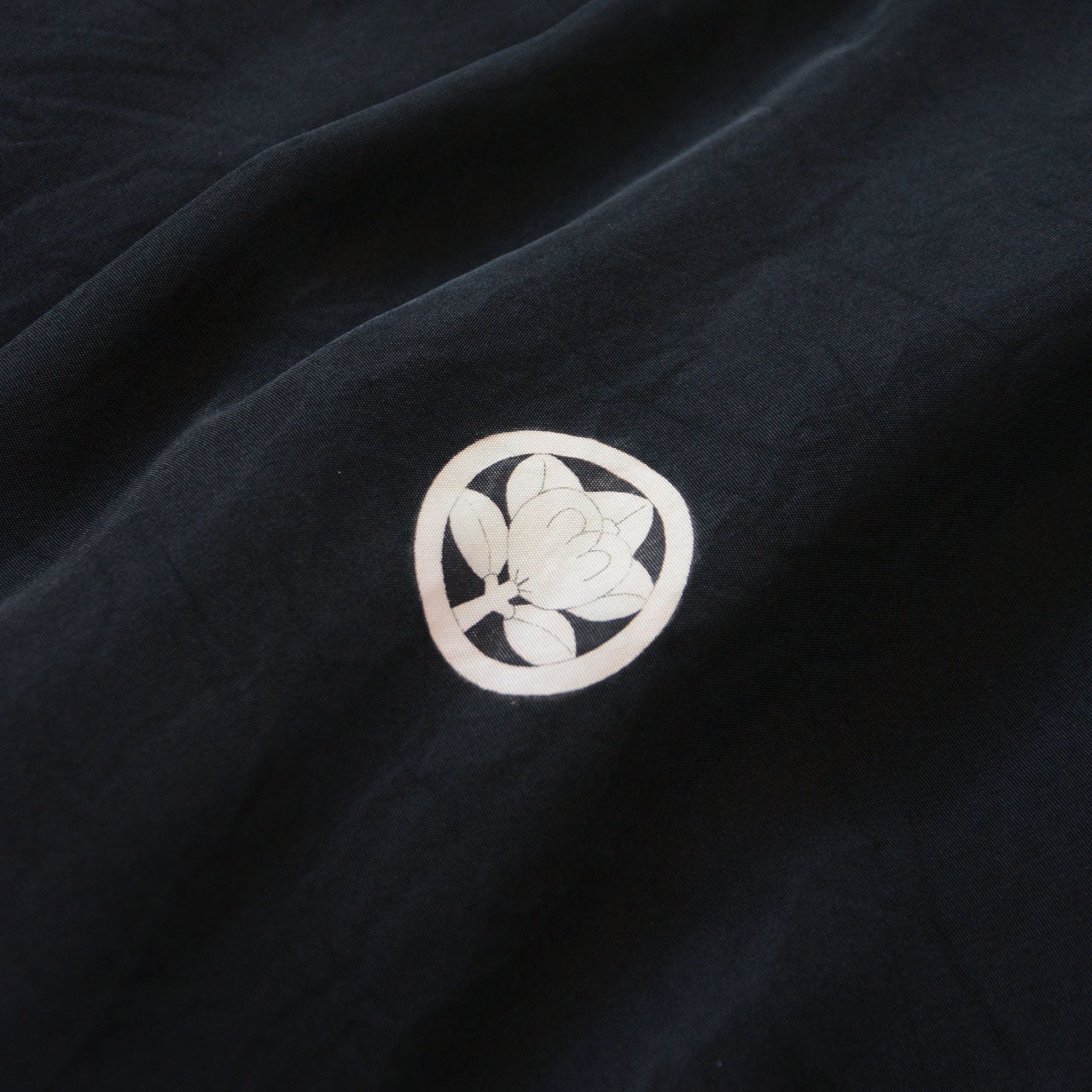 Close-up of family crest (kamon) on men's black silk itsutsumon haori