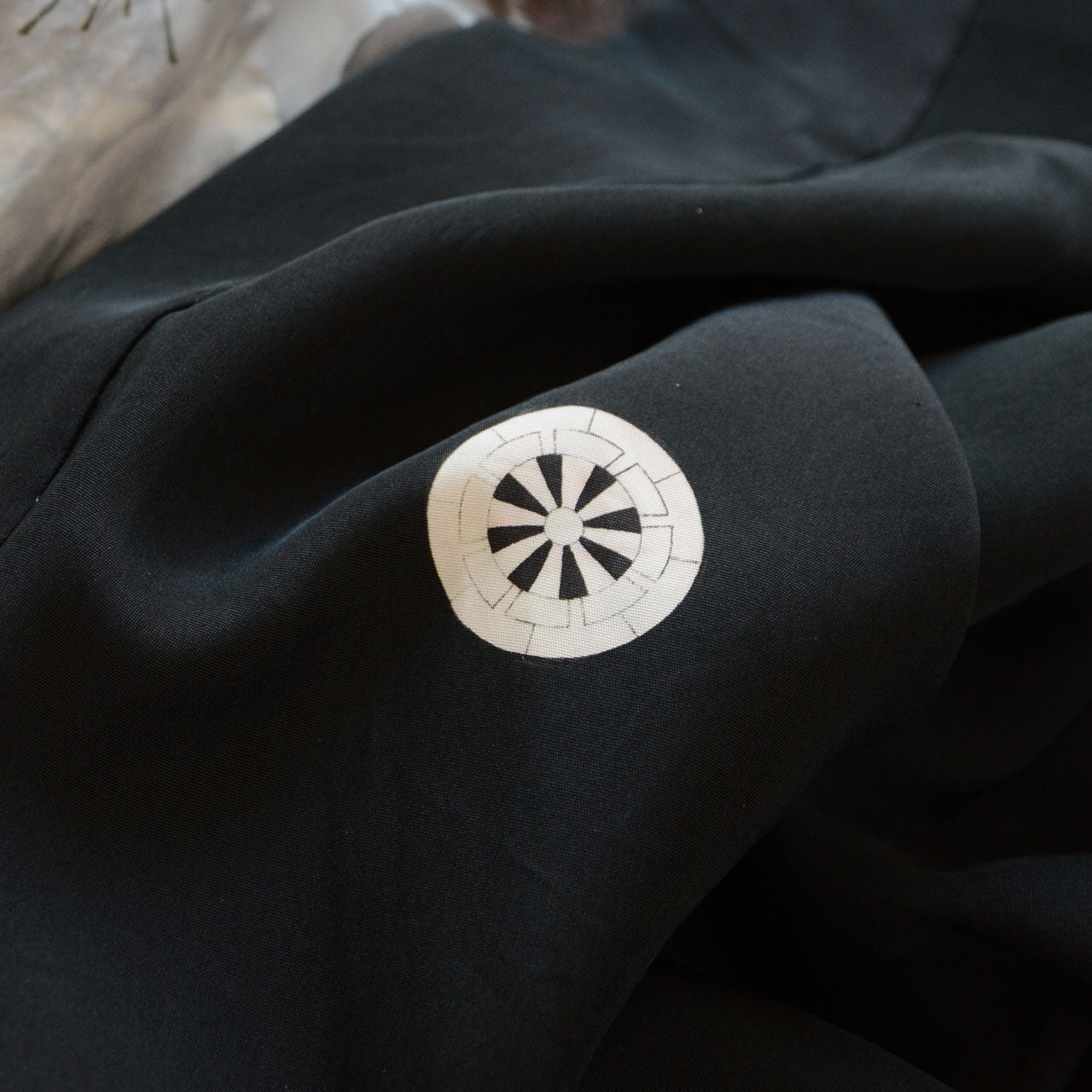 Close-up of Maruni Genji-guruma kamon crest on black silk haori, white circular family crest, montsuki, Japan vintage