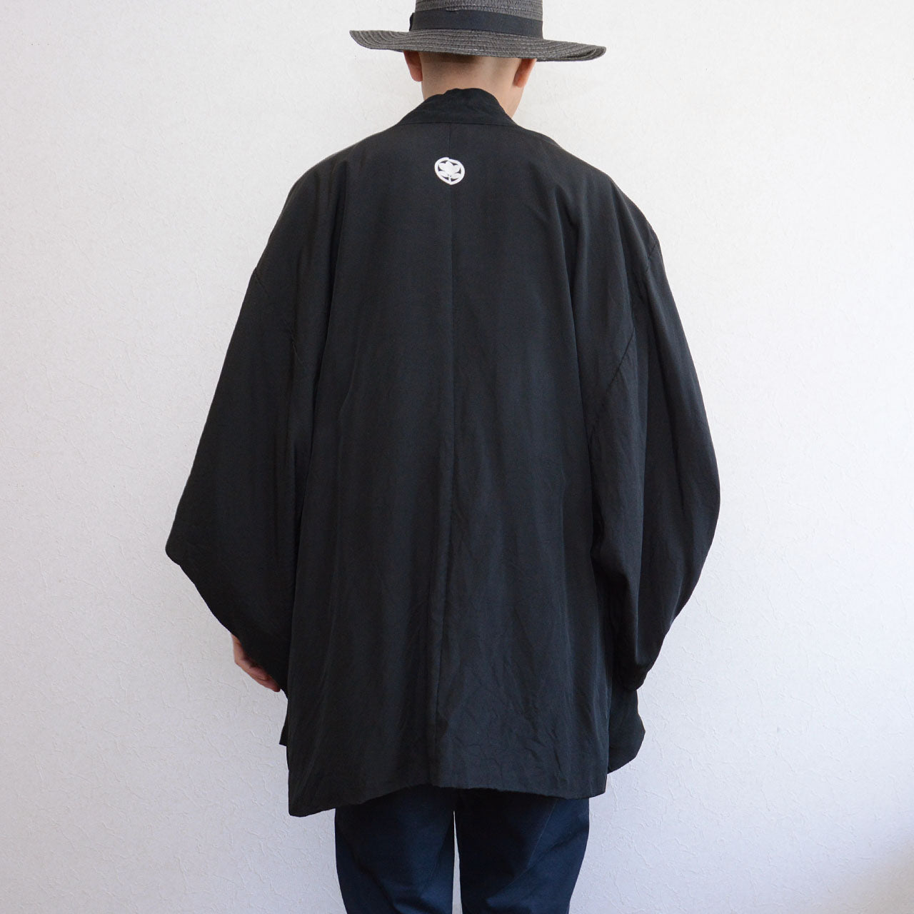 Model wearing men's black silk itsutsumon haori jacket, back view