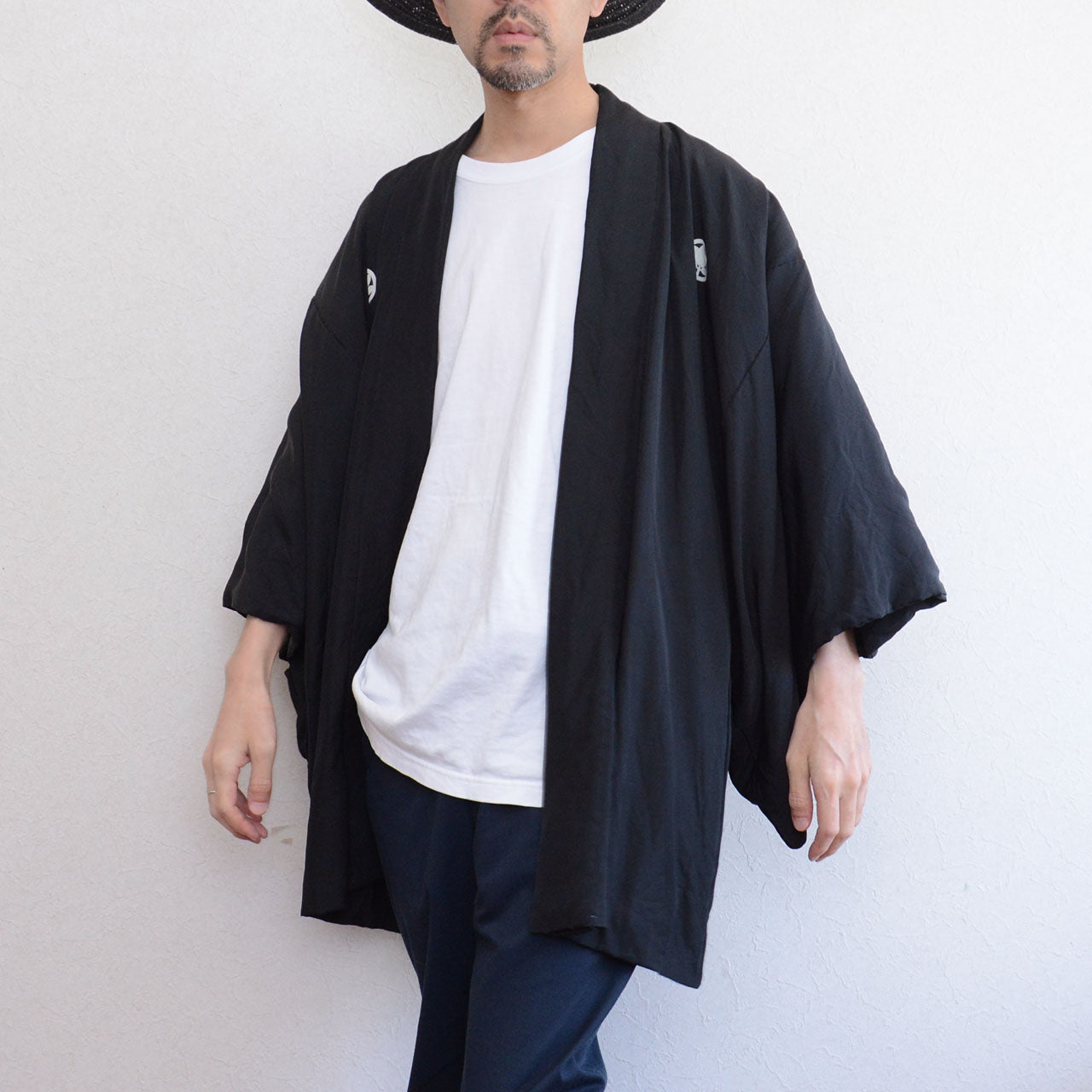 Model in motion wearing men's black silk itsutsumon haori jacket, front view