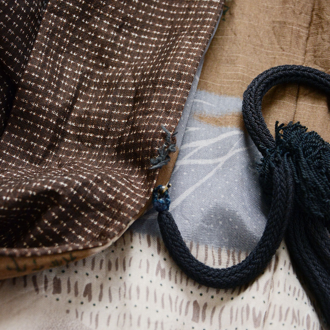 Detail of haori-himo attachment point showing missing himo-chi loop on one side, cord tied through frayed fabric, Japanese vintage haori jacket condition detail