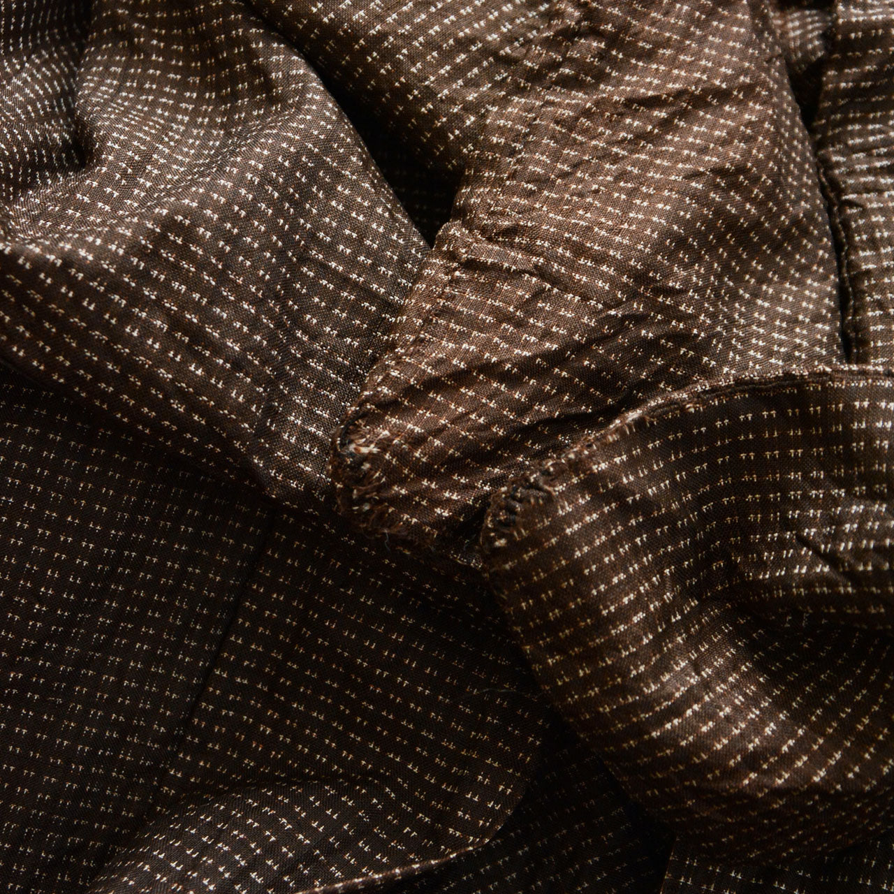 Sleeve of men's Japanese vintage haori jacket showing fabric tear, brown silk komon weave, condition detail