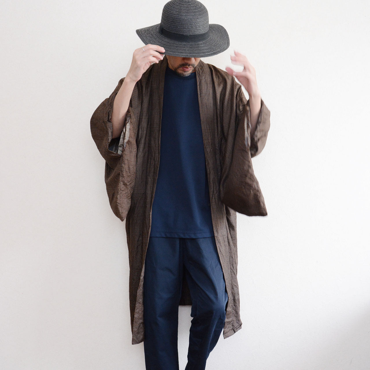 Men's Japanese vintage haori jacket in brown silk komon, front view with dynamic drape, open style worn over navy t-shirt and trousers, Showa era