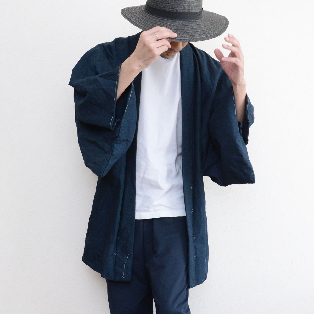 Deep blue-green Japanese vintage men's haori worn with a white T-shirt, dark trousers and a dark brimmed hat.